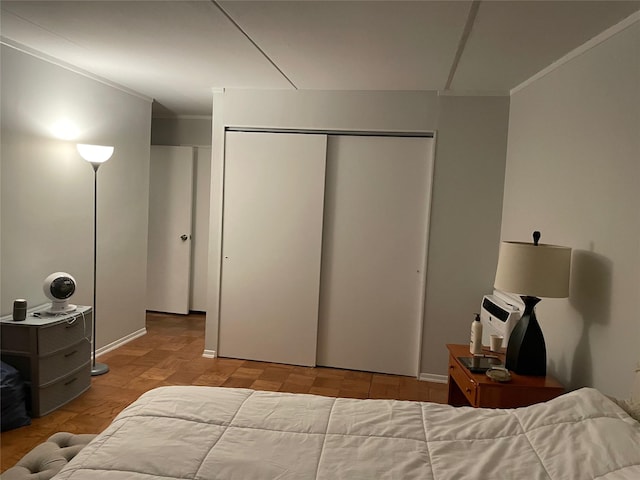 bedroom featuring ornamental molding, light parquet flooring, and a closet