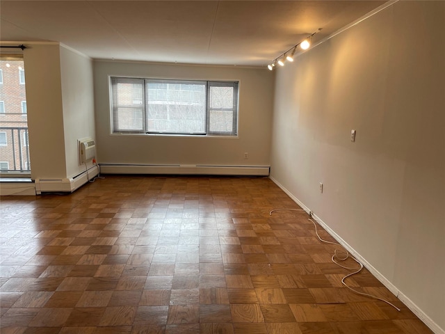 empty room featuring a baseboard heating unit, track lighting, ornamental molding, and parquet flooring