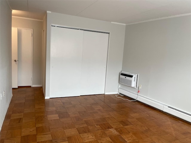 unfurnished bedroom featuring a baseboard heating unit, a wall mounted air conditioner, dark parquet floors, ornamental molding, and a closet