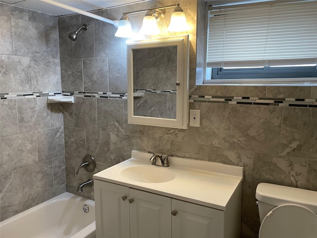 full bathroom featuring tiled shower / bath, tile walls, vanity, and toilet