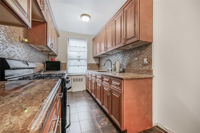 kitchen featuring dark tile patterned floors, light stone countertops, decorative backsplash, and black range with gas cooktop