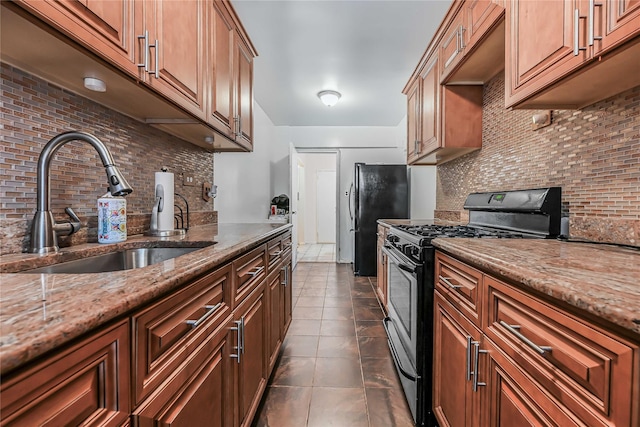 kitchen featuring light stone countertops, sink, stainless steel gas range, and backsplash