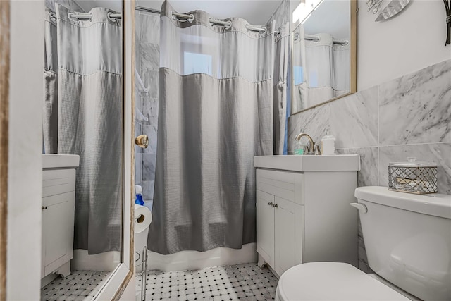 bathroom with tile walls, vanity, toilet, and a shower with shower curtain