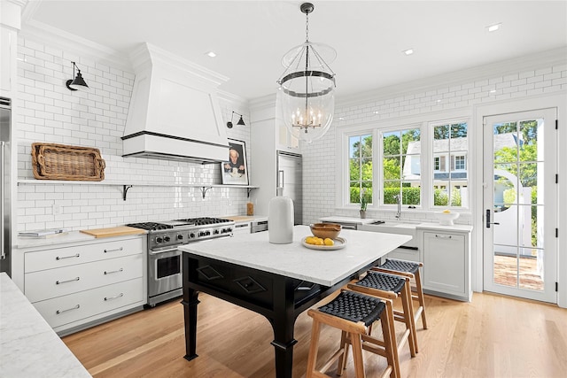 kitchen with premium range hood, crown molding, decorative light fixtures, high quality appliances, and white cabinets