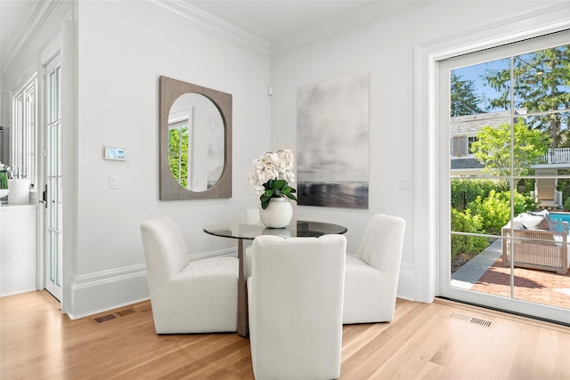 dining area with ornamental molding and light hardwood / wood-style flooring