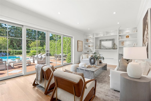 living room featuring crown molding, built in features, light hardwood / wood-style floors, and french doors