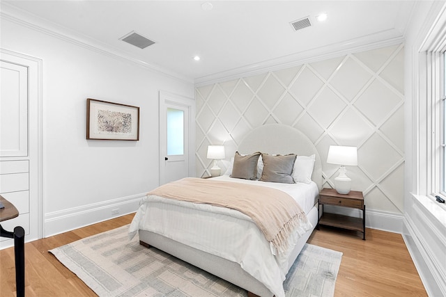 bedroom featuring multiple windows, ornamental molding, and light hardwood / wood-style flooring