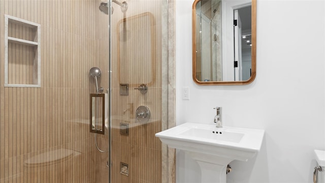 bathroom with sink and a shower with door