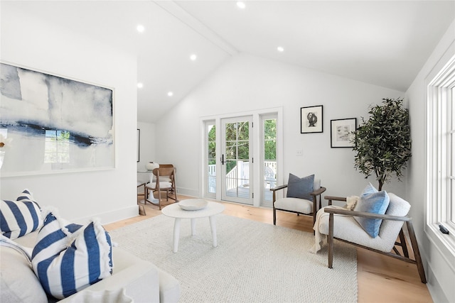 living room featuring lofted ceiling with beams and light hardwood / wood-style flooring