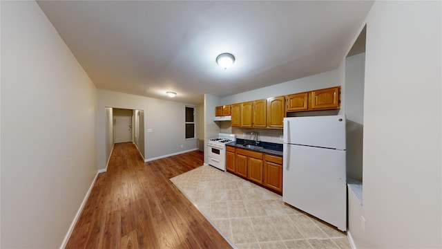 kitchen with sink, white appliances, and light hardwood / wood-style floors