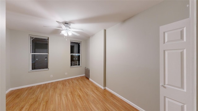 empty room featuring radiator heating unit, light hardwood / wood-style flooring, and ceiling fan