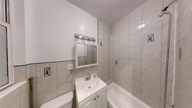 bathroom with toilet, tile walls, vanity, and a shower with door