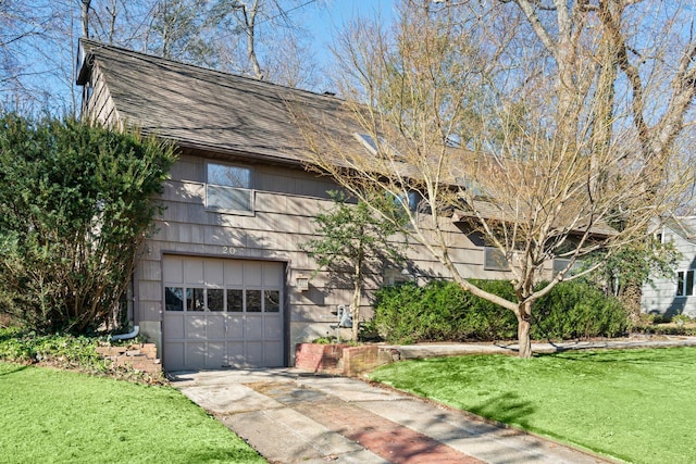 view of front of property with a front yard, concrete driveway, a garage, and roof with shingles