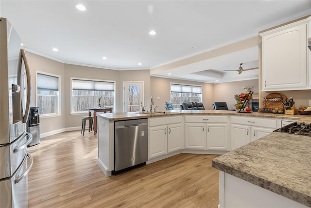 kitchen with sink, light hardwood / wood-style flooring, appliances with stainless steel finishes, white cabinetry, and kitchen peninsula