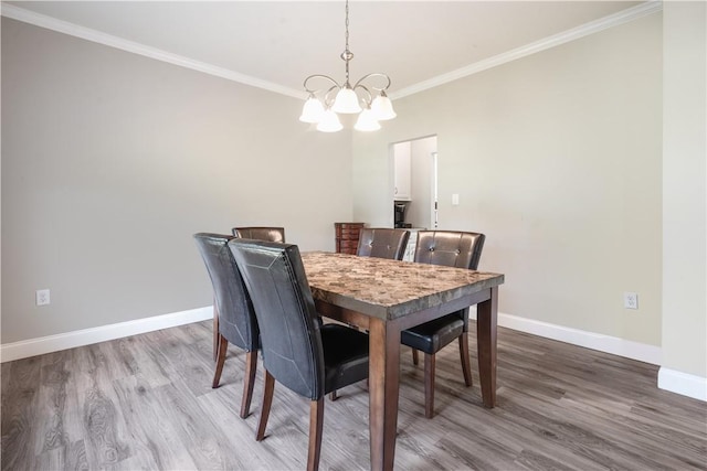 dining room featuring hardwood / wood-style flooring, crown molding, and a notable chandelier