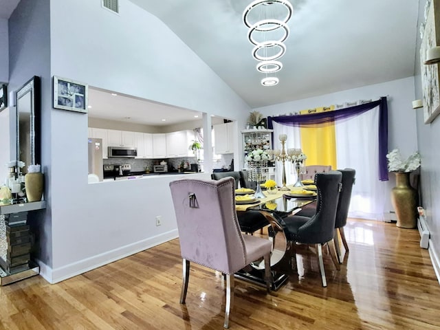 dining room with an inviting chandelier, a baseboard radiator, light hardwood / wood-style flooring, and a wealth of natural light