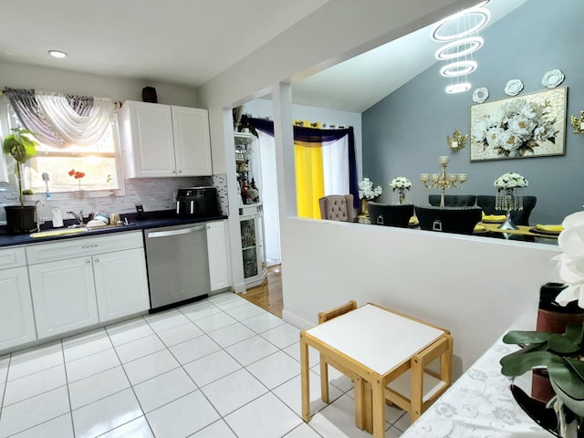 kitchen with light tile patterned flooring, white cabinetry, sink, decorative backsplash, and stainless steel dishwasher