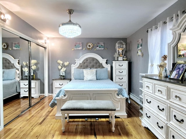 bedroom with a notable chandelier, light hardwood / wood-style floors, and a closet