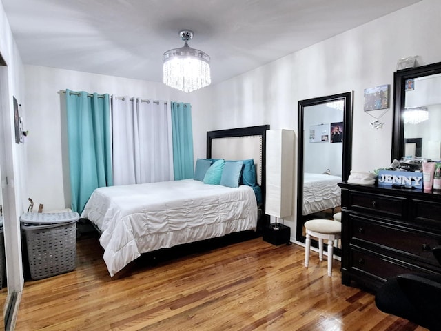 bedroom with an inviting chandelier and light hardwood / wood-style flooring