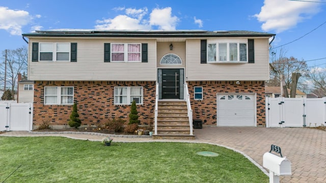 split foyer home featuring a garage, a front yard, and solar panels