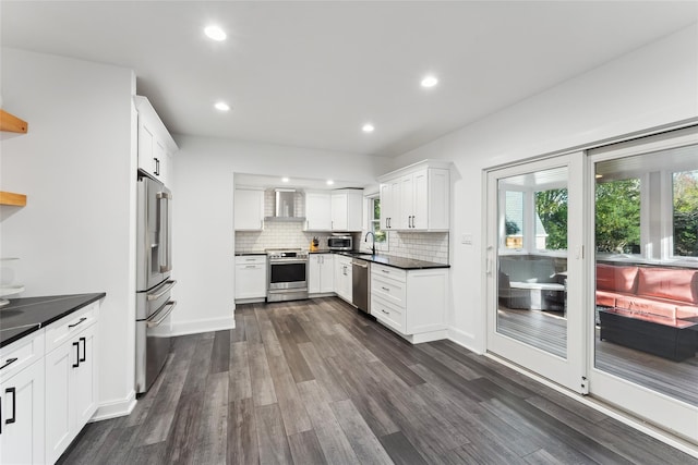 kitchen with tasteful backsplash, dark wood finished floors, dark countertops, wall chimney exhaust hood, and stainless steel appliances