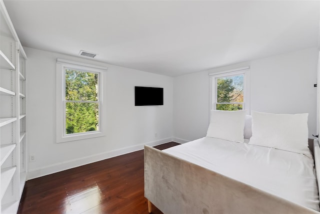 bedroom with dark wood-style floors, visible vents, and baseboards