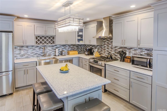 kitchen featuring appliances with stainless steel finishes, a breakfast bar, sink, and wall chimney exhaust hood