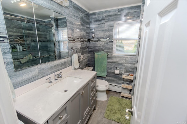 bathroom with tile walls, vanity, ornamental molding, toilet, and walk in shower