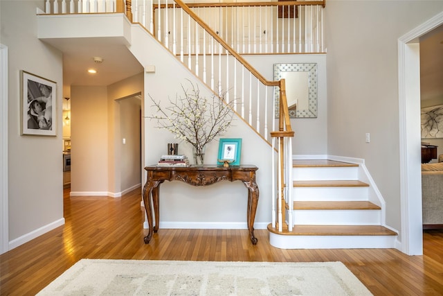 stairs with hardwood / wood-style floors and a towering ceiling