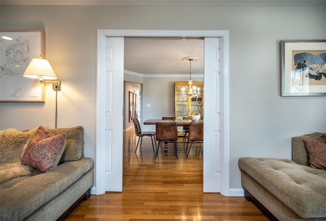 living room featuring ornamental molding, wood-type flooring, and a notable chandelier