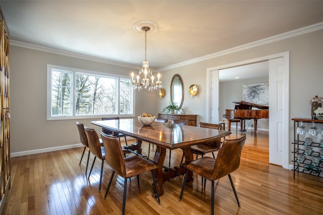 dining room with ornamental molding, an inviting chandelier, and light hardwood / wood-style flooring