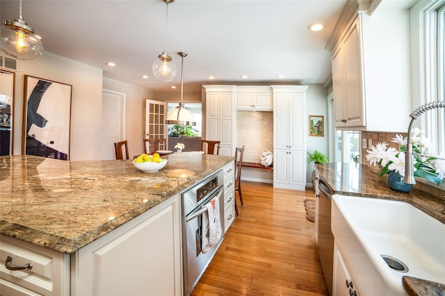 kitchen with light stone counters, stainless steel appliances, a kitchen island, and hanging light fixtures