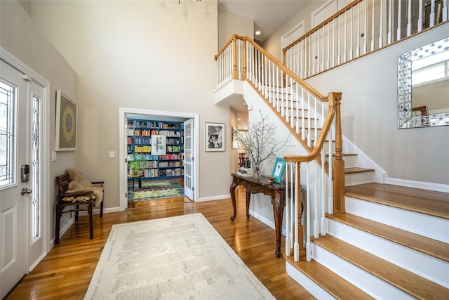 entryway with hardwood / wood-style flooring and a towering ceiling