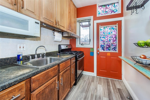 kitchen with gas range, backsplash, sink, and light wood-type flooring