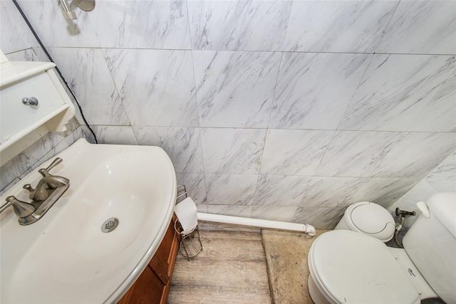 bathroom with vanity, tile walls, and toilet