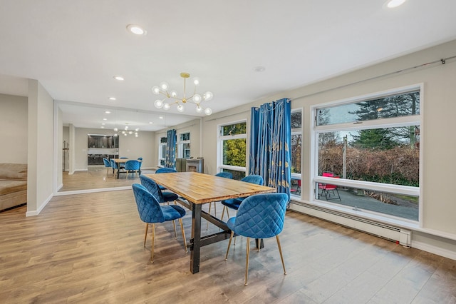 dining room featuring a baseboard heating unit, light hardwood / wood-style floors, and a chandelier