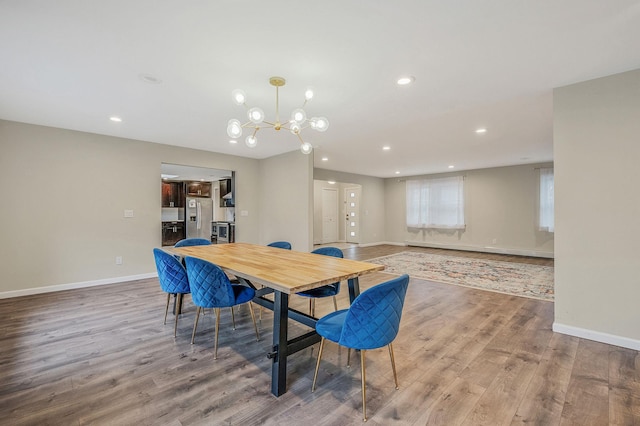 dining space featuring a baseboard radiator, light hardwood / wood-style floors, and a notable chandelier