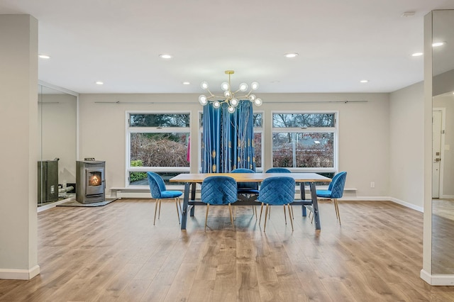 dining room featuring plenty of natural light, a wood stove, a chandelier, and light wood-type flooring