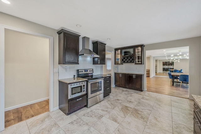 kitchen featuring appliances with stainless steel finishes, tasteful backsplash, light tile patterned floors, dark brown cabinetry, and wall chimney range hood