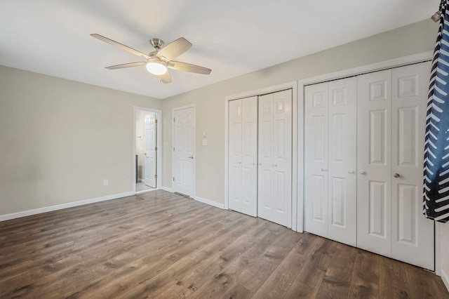 unfurnished bedroom with hardwood / wood-style flooring, ceiling fan, and two closets