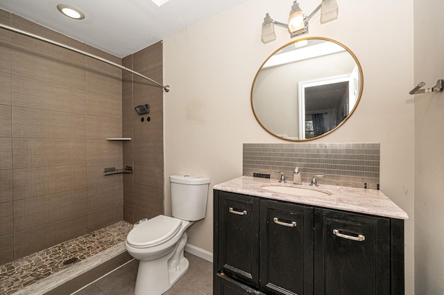 bathroom with a tile shower, tasteful backsplash, tile patterned flooring, vanity, and toilet