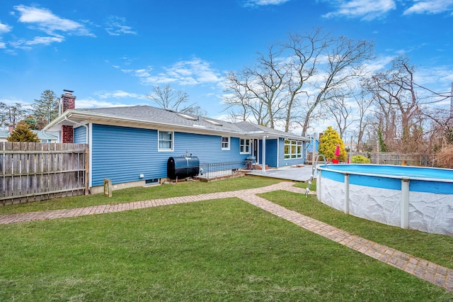 back of house featuring a fenced in pool and a yard