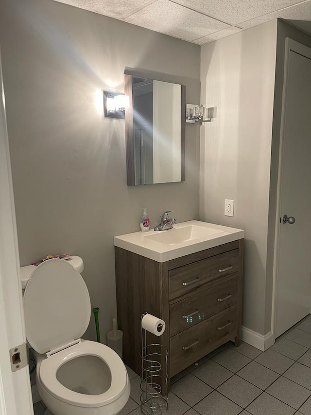 bathroom featuring vanity, a paneled ceiling, tile patterned floors, and toilet