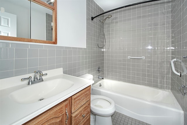 full bathroom with tiled shower / bath, tile walls, vanity, toilet, and tile patterned floors