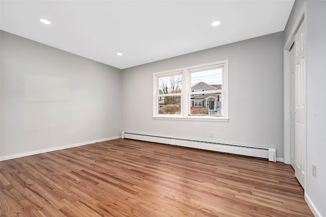 empty room with a baseboard radiator and light hardwood / wood-style flooring