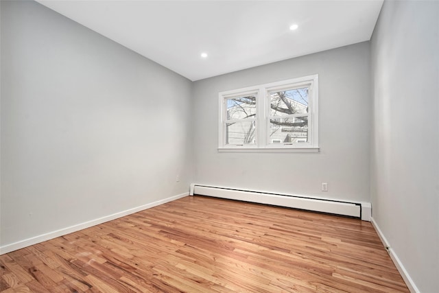 unfurnished room featuring a baseboard radiator and light wood-type flooring