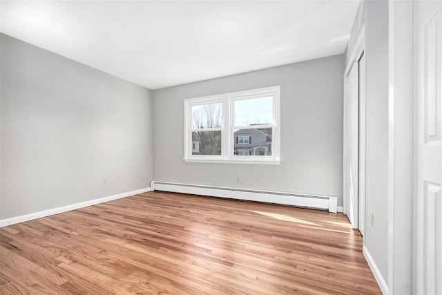 unfurnished bedroom with a baseboard radiator, light wood-type flooring, and a closet