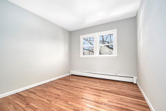 empty room with a baseboard heating unit and light hardwood / wood-style floors