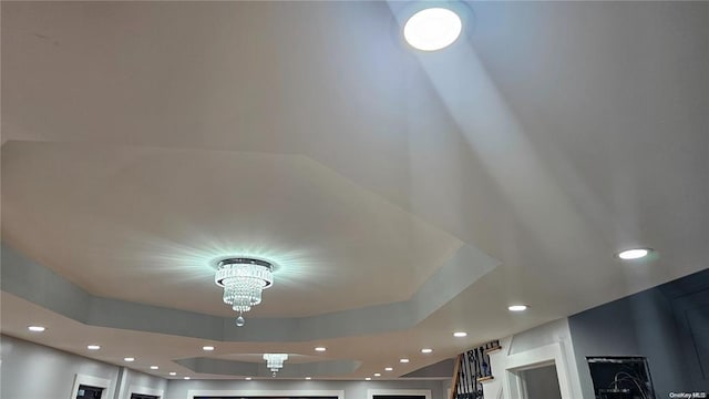 interior details featuring a notable chandelier and a raised ceiling