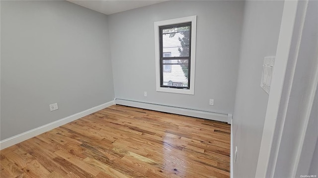 empty room with a baseboard heating unit and light hardwood / wood-style floors